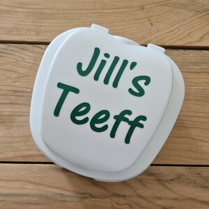 May include: White plastic container with a green vinyl sticker that says "Jill's Teeff".
