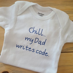 May include: White baby onesie with blue text that reads "Chill... my Dad writes code."