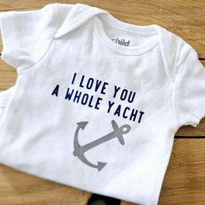 May include: White baby onesie with a blue anchor and the text "I love you a whole yacht".