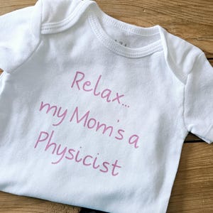May include: White baby onesie with pink text that reads "Relax... my Mom's a Physicist".