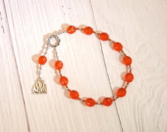 May include: Orange crystal beads with silver accents and a silver charm in the shape of a flame. The beads are strung on a silver chain.