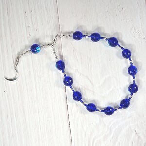 May include: A blue crystal beaded necklace with a silver crescent moon charm.