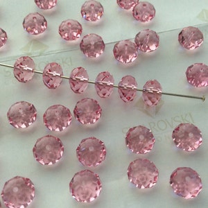 Pode incluir: Uma cole&ccedil;&atilde;o de contas de cristal rosa, algumas enfiadas em um fio, outras soltas. As contas s&atilde;o facetadas e t&ecirc;m uma forma redonda.