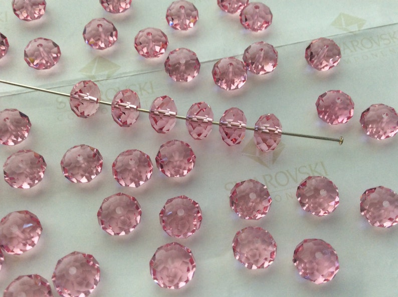 Pode incluir: Uma cole&ccedil;&atilde;o de contas de cristal rosa, algumas enfiadas em um fio, outras soltas. As contas s&atilde;o facetadas e t&ecirc;m uma forma redonda.