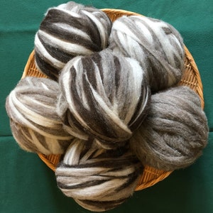 May include: A basket filled with six balls of yarn. The yarn is a mix of black and white, and some balls are a solid gray color.