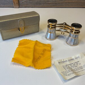Peut inclure: Lunettes d'opéra dorées avec un motif en nacre, dans un étui doré avec un chiffon de nettoyage jaune et une petite carte d'instructions qui indique "ANTI-FOGGING CLEANING CLOTH This ANTI-FOGGING CLEANING CLOTH not only cleans but prevents fog from on the surface of lenses."