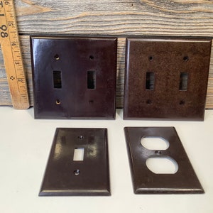 Puede incluir: Cuatro placas de interruptor eléctrico de baquelita marrón vintage. Dos son placas de interruptor doble, una es una placa de interruptor simple y una es una placa de tomacorriente simple.