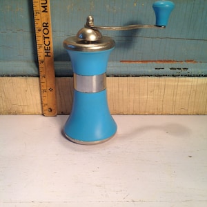 May include: A blue and silver pepper grinder with a crank handle. The grinder is made of plastic and metal. The handle is made of plastic and has a blue knob.