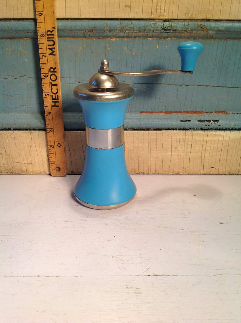 May include: A blue and silver pepper grinder with a crank handle. The grinder is made of plastic and metal. The handle is made of plastic and has a blue knob.