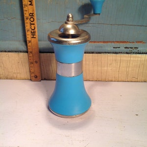 May include: A blue and silver manual pepper grinder with a crank handle. The grinder is made of ceramic and metal.
