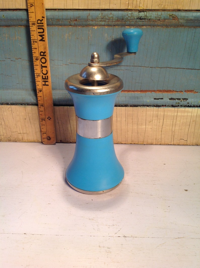 May include: A blue and silver manual pepper grinder with a crank handle. The grinder is made of ceramic and metal.