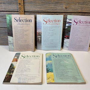 Könnte beinhalten: Eine Sammlung von Vintage-Magazinen "Sélection du Reader's Digest". Die Zeitschriften haben farbenfrohe Umschläge mit französischem Text und Illustrationen. Die Zeitschriften sind auf einer weißen Oberfläche vor einem Holzgrund angeordnet.
