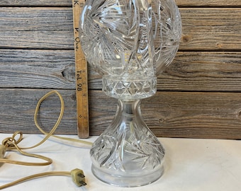 May include: Clear crystal table lamp with a round, patterned shade and a decorative base. The lamp has a cord and plug. The lamp is approximately 10 inches tall.