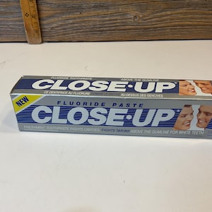 May include: A silver and blue Close-Up toothpaste box with a white and blue stripe design. The box features the text "Fluoride Paste Close-Up" and "Freshmint Toothpaste Fights Cavities Fights Tartar Above the Gumline for White Teeth".