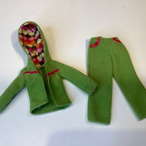 Peut inclure: Une veste à capuche verte avec une doublure à motifs colorés et un pantalon vert assorti. La veste a des bordures rouges et le pantalon a des accents rouges.