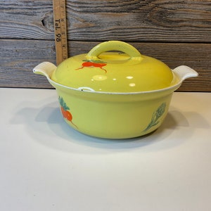 May include: Yellow enamel cast iron pot with a lid. The pot has a white handle and is decorated with a green and red radish design.