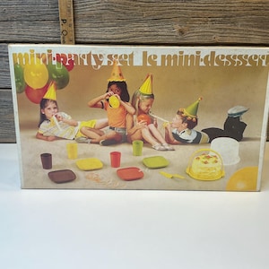 May include: A vintage mini party set box with a retro illustration of children at a party. The box shows party hats, balloons, plates, cups, and a cake. The text "mini party set le mini dessert" is displayed on the box.