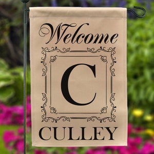 May include: A beige welcome garden flag with a black ornate frame and the letter "C" inside. The text "Welcome" and the name "CULLEY" are printed in black below the frame.
