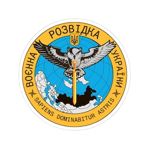 May include: A round sticker featuring a stylized owl with outstretched wings, holding a sword. The design includes text in Ukrainian and Latin, set against a blue globe and a yellow border.