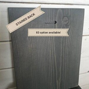 May include: The back of a wooden sign with a stained gray finish. The sign has a hole in the top for hanging. A label reads "$3 option available!"