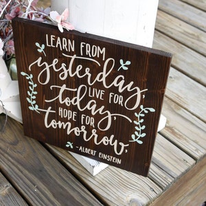 May include: A dark brown wooden sign with white and light blue lettering. The sign reads "Learn from yesterday, live for today, hope for tomorrow." - Albert Einstein.