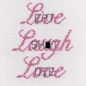 May include: Pink cross-stitch embroidery with the text "Live Eat Laugh Shoot Love Die" in a cursive font.