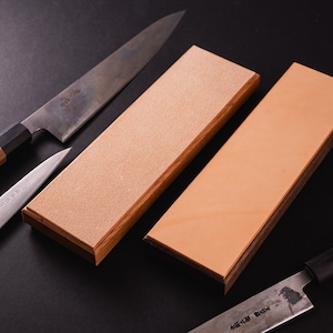 May include: Two wooden sharpening stones, one with a rough surface and one with a smooth surface, and three Japanese knives with wooden handles.