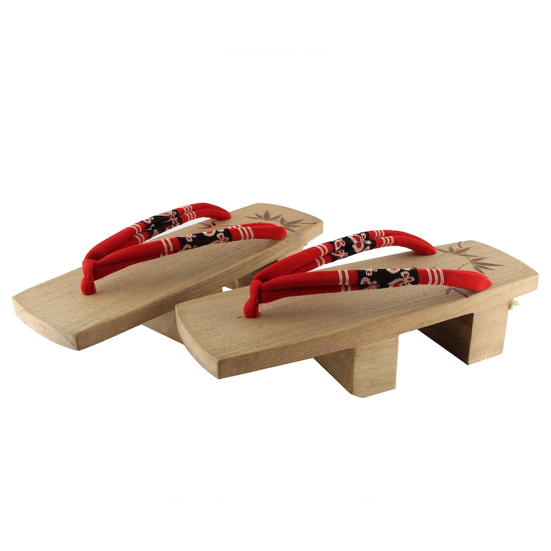 May include: A pair of wooden Japanese sandals, known as geta, with red fabric straps and a floral pattern. The sandals have a raised wooden base and are traditionally worn with a kimono.