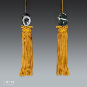 May include: Two gold tassel ornaments with black and white agate beads. The beads have a swirling pattern.