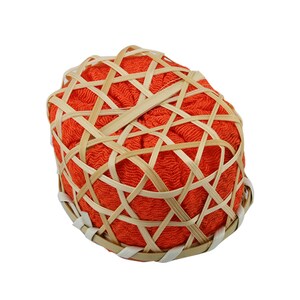 May include: Orange fabric wrapped in a woven bamboo basket. The basket is oval shaped and has a woven pattern.