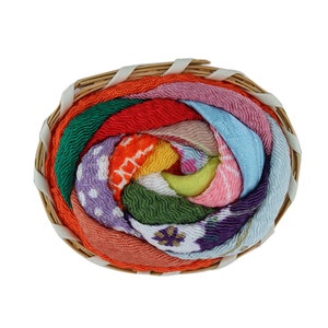 May include: A colorful fabric rose in a woven basket. The rose is made of many different fabrics, each with a different pattern and color. The rose is a beautiful and unique piece of art.