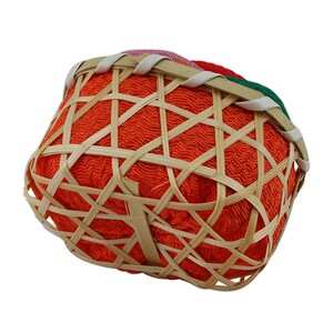 May include: A small, round, orange woven basket with a bamboo frame. The basket is lined with a red fabric and has a colorful woven trim around the top.