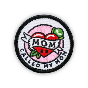 May include: A white and black embroidered patch with a pink background. The patch features a red heart with the word "MOM" on a banner. The text "Called My Mom" is written around the heart.