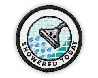 May include: A white round embroidered patch with a black border. The patch features a shower head with water droplets and the text "Showered Today".