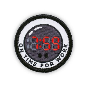 May include: A round, embroidered patch with a black border and a white inner ring. The patch features a digital clock face displaying "8:59" in red digits. The text "ON TIME FOR WORK" is arched around the clock face.