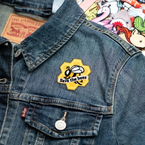 May include: A denim jacket with a yellow and black bee patch that says "Save the bees".