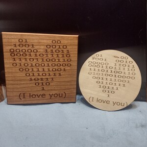 May include: Two wooden plaques with the phrase "(I love you)" written in binary code. The plaques are made of light brown wood and have a natural finish.