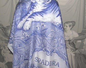 May include: A blue and white silk scarf featuring a detailed illustration of a tiger, surrounded by tropical foliage. The scarf has the word "SPADIRA" in a decorative banner. The design is reminiscent of classic porcelain patterns.