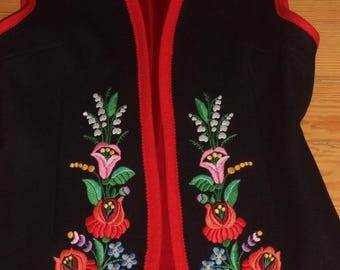 May include: Black vest with red trim and lining, featuring colorful floral embroidery. The embroidery includes red roses, pink and white flowers, and blue and purple accents. The vest is sleeveless and has a V-neck.