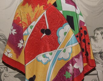 May include: A colorful silk scarf with a geometric pattern in shades of red, yellow, green, blue, white, and black. The scarf features a variety of abstract shapes and designs, including flowers, leaves, and geometric shapes.