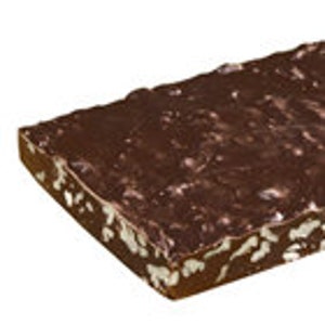 May include: A large slab of chocolate fudge topped with chopped nuts. The fudge is a dark brown color and the nuts are a light brown color.