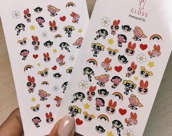 May include: Two sheets of white paper with colorful stickers featuring the Powerpuff Girls characters. The top sheet says "GLOSS Powerpuff" and the bottom sheet says "GLOSS Powerpuff XL".