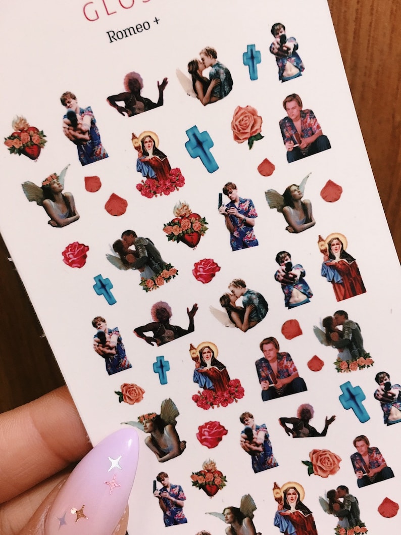 May include: A sheet of nail art stickers featuring images of a couple, a cross, a heart, a rose, and a woman in a religious robe. The stickers are on a white background and have a glossy finish.