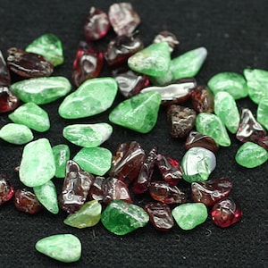 May include: A collection of green and red gemstones. The gemstones are various shapes and sizes.