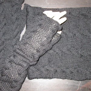 May include: A pair of black knitted fingerless gloves and a matching black knitted scarf. The gloves have a cable knit pattern and the scarf has a textured pattern.