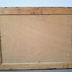 May include: Back of a rectangular wooden picture frame. The frame is made of light brown wood with a darker brown border. Metal chain and hardware are attached for hanging. The back is a light brown wood panel.