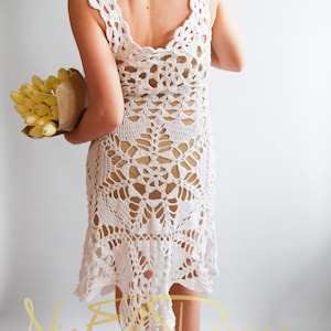 May include: White crochet dress with a low back and a scalloped hem. The dress is made with a delicate openwork pattern.