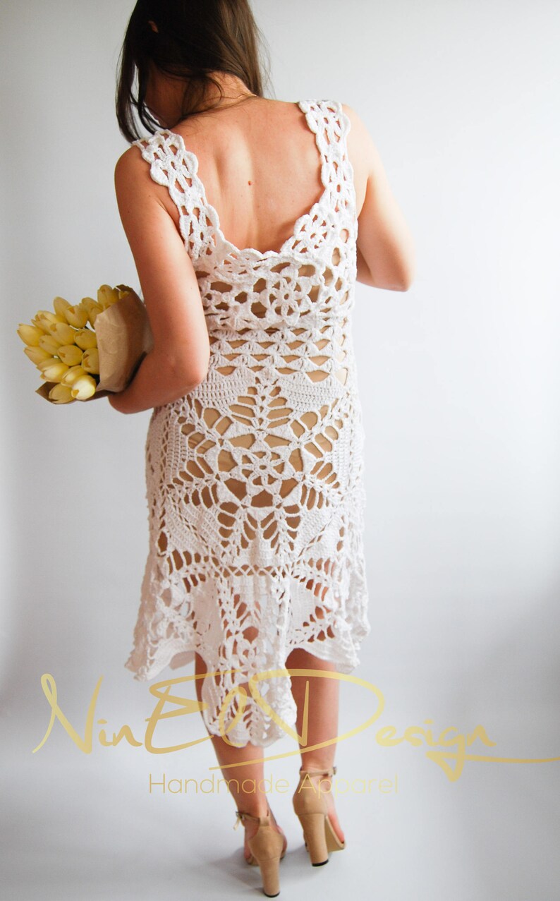 May include: White crochet dress with a low back and a scalloped hem. The dress is made with a delicate openwork pattern.