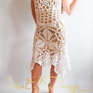May include: White crochet dress with a delicate, lacy pattern. The dress has a sleeveless design and a flowing skirt.