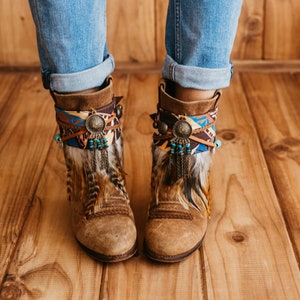May include: Brown suede ankle boots with colourful patterned fabric and feather trim around the ankle.
